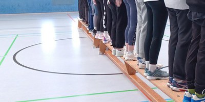 Titelbild zeigt Gruppe von hinten, nur Beine auf Bank stehende