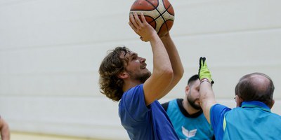 Das Bild zeigt einen Mann im Rollstuhl, der einen Basketball werfen möchte beim Rollstuhl-Basketball.