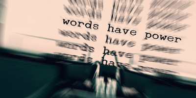 Man sieht leicht verwischt eine Schreibmaschine. Auf dem eingelegten papier steht "Words have power" (englisch für "Worte haben Macht")