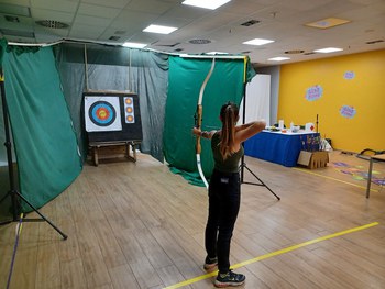 ein Mädchen schießt mit Bogen auf eine Zielscheibe